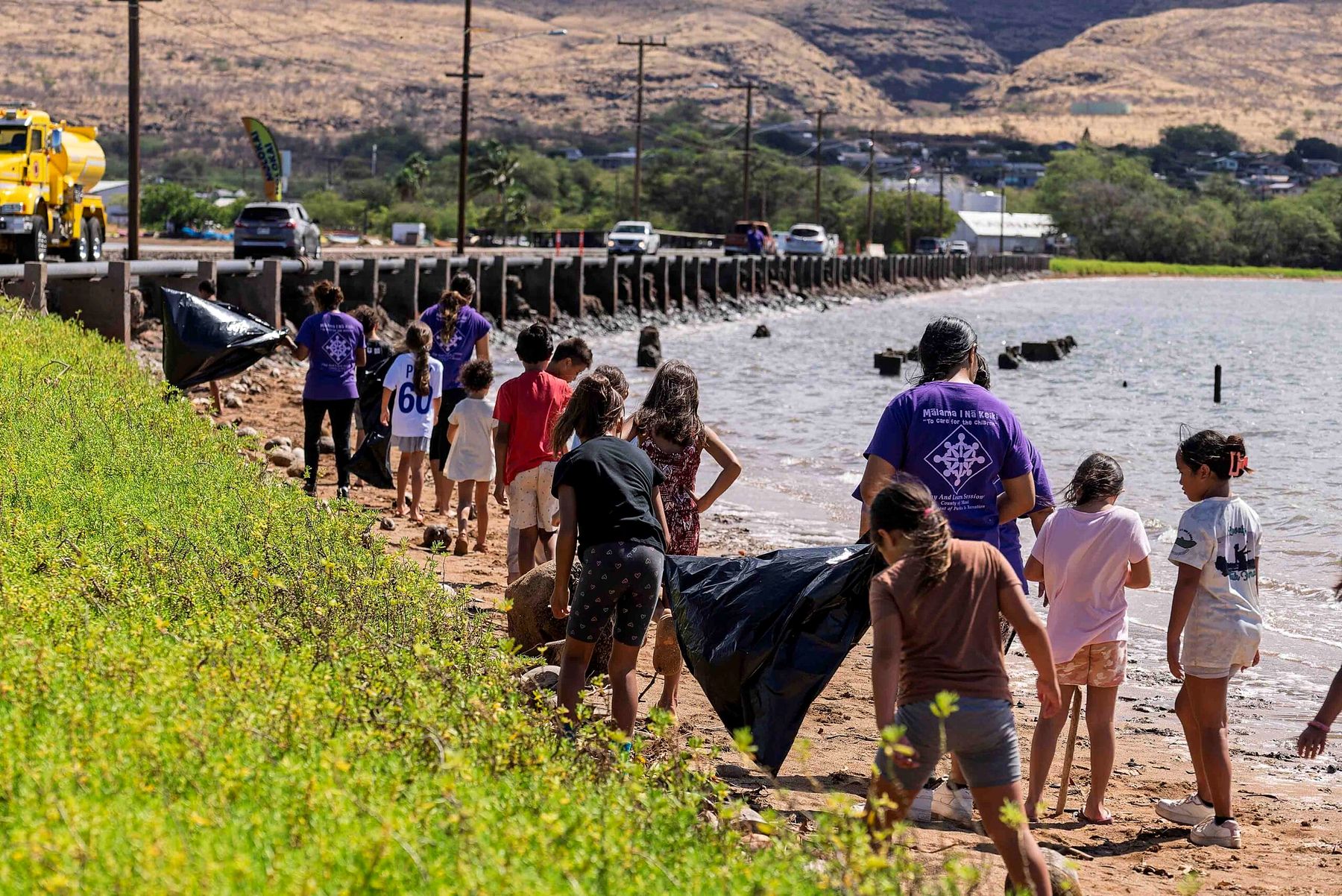Keiki and volunteers clean up the shoreline beside the Kaunakakai wharf