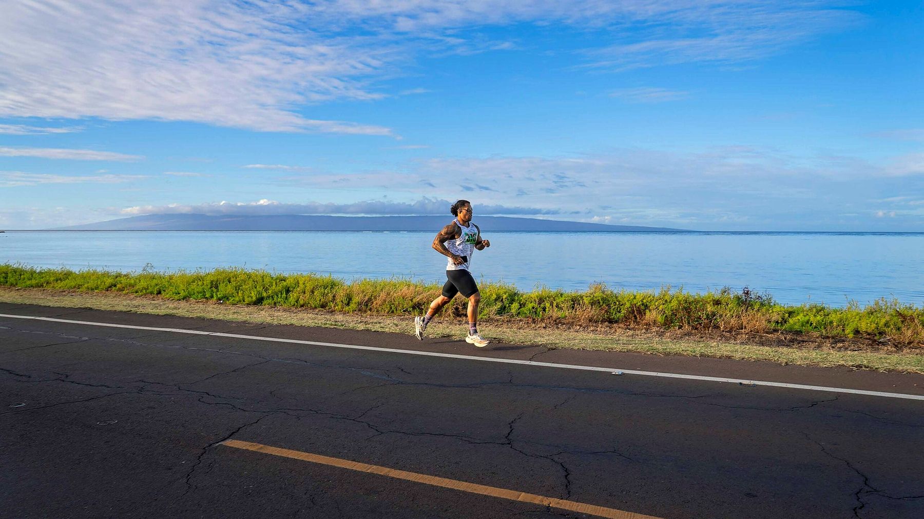 A runner on Molokaʻi's coastal road with Lānaʻi on the horizon