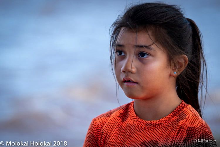 A young girl in an orange race shirt at the Hoʻolauleʻa