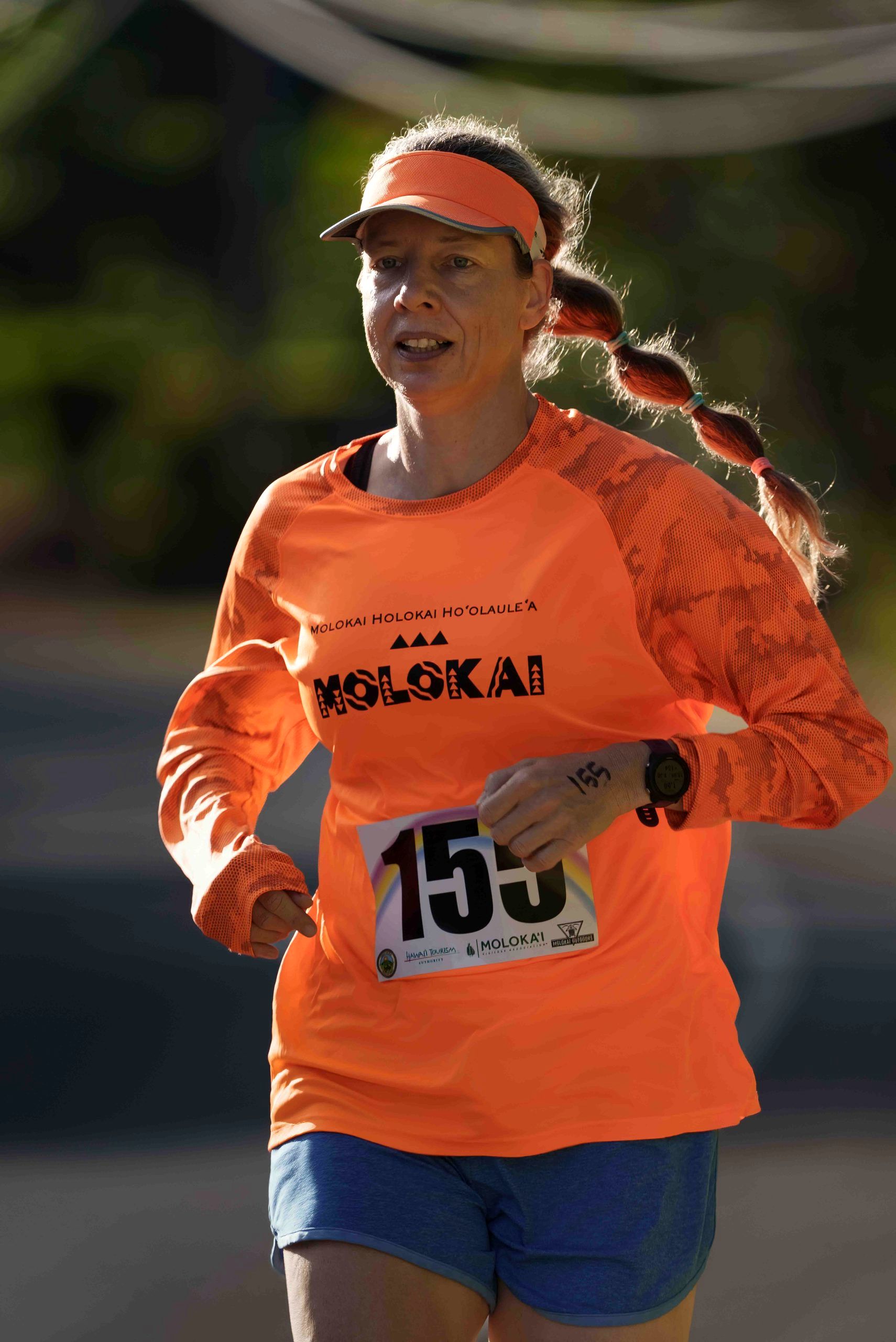 A smiling runner in an orange Molokai shirt