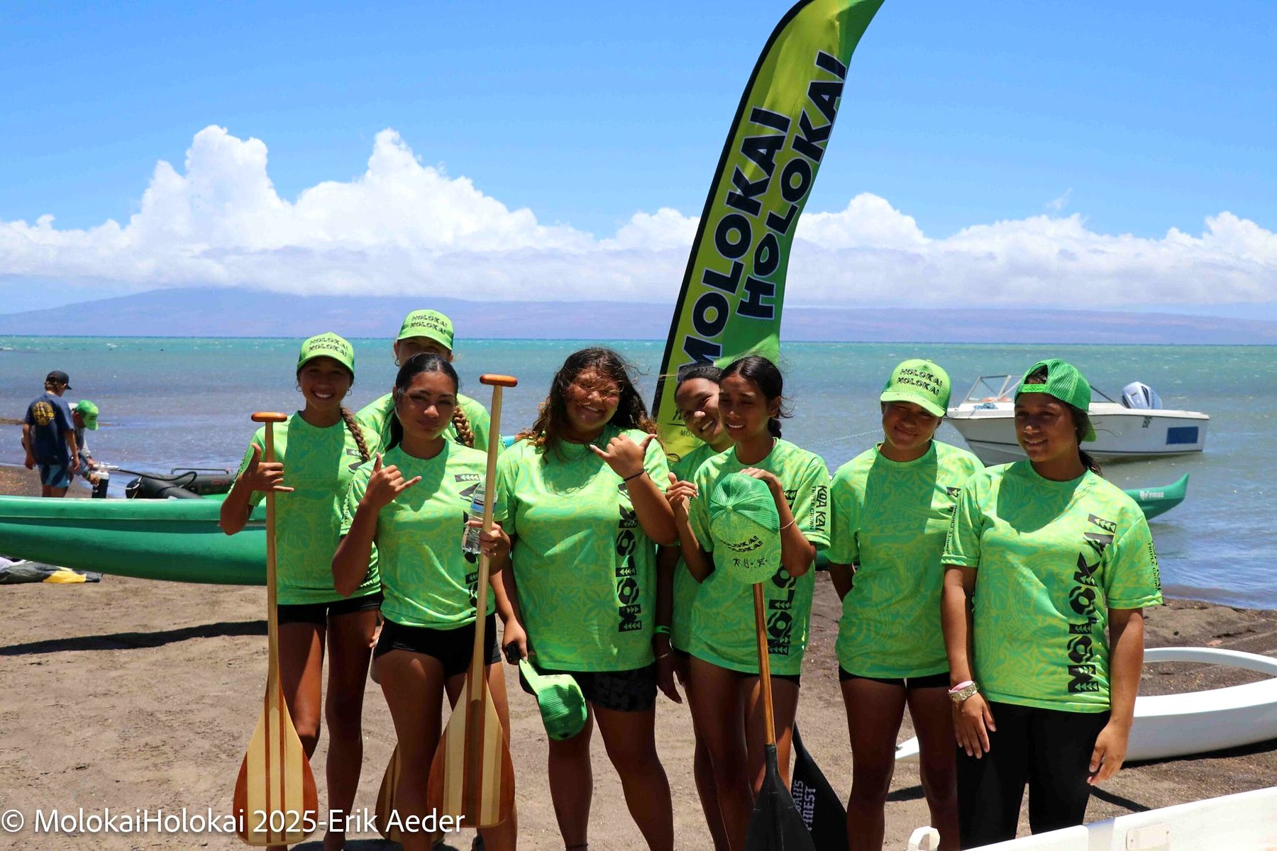 Youth paddlers in green shirts holding their paddles